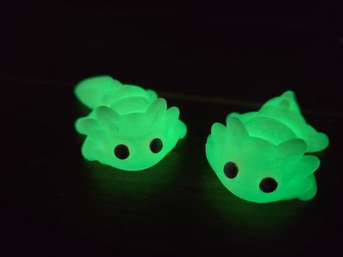 Two 3D printed axolotls glowing bright green in the dark, printed in EconoFil Glow Green PLA
