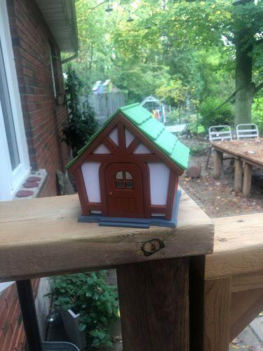 3D printed cottage birdhouse with wood-toned walls printed in EconoFil Brown PLA, photographed outdoors