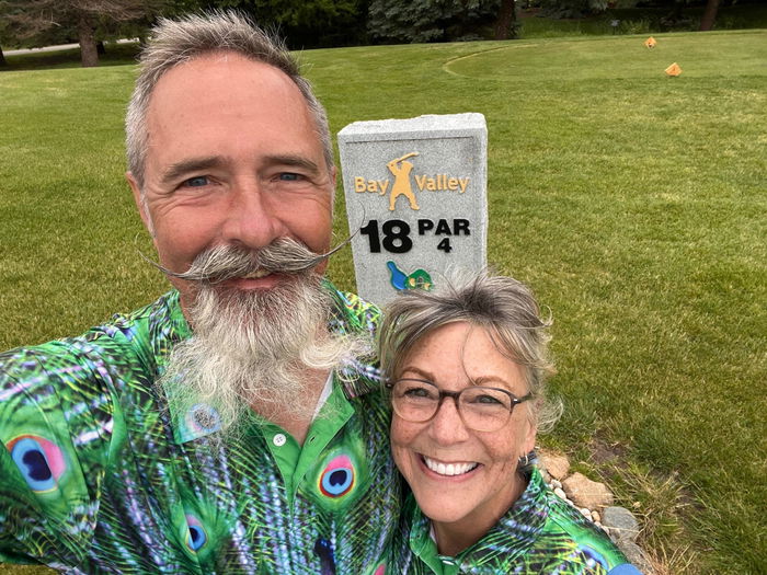 Couple at hole 18 in matching Obnoxious Golf peacock polos